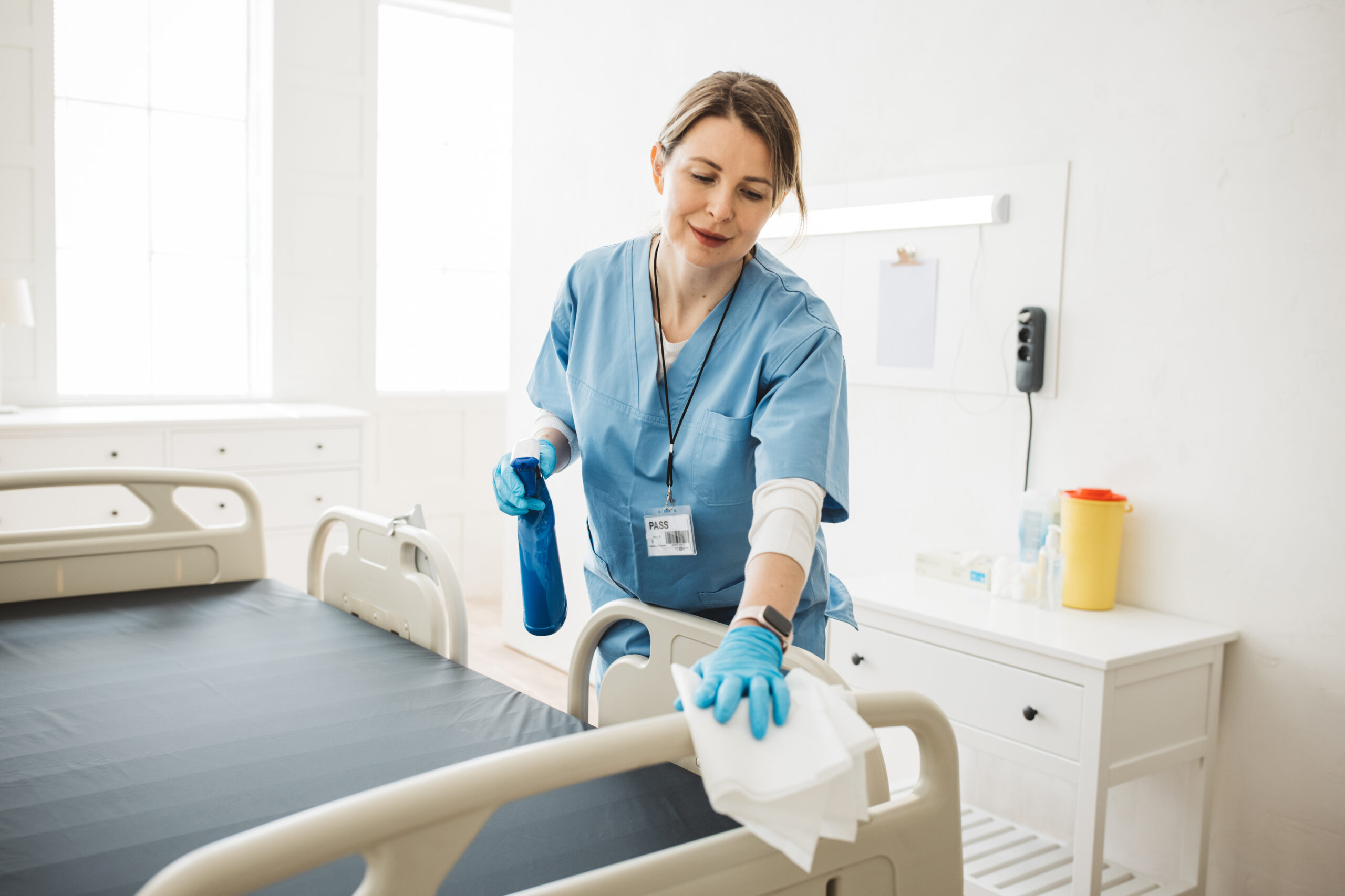 Cleaner disinfecting a medical patient room in a healthcare facility