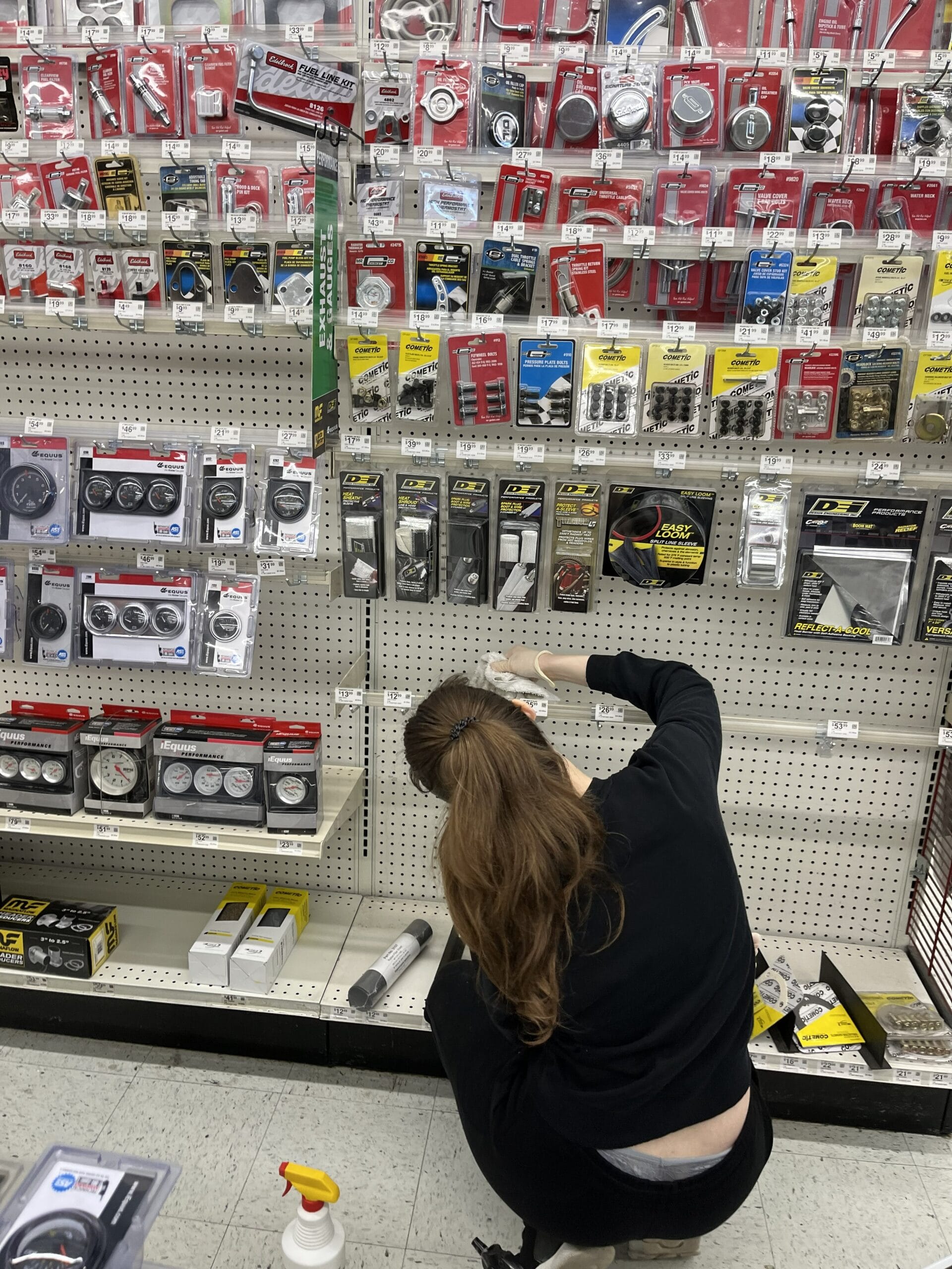 Commercial cleaning technician cleaning lower retail display shelves